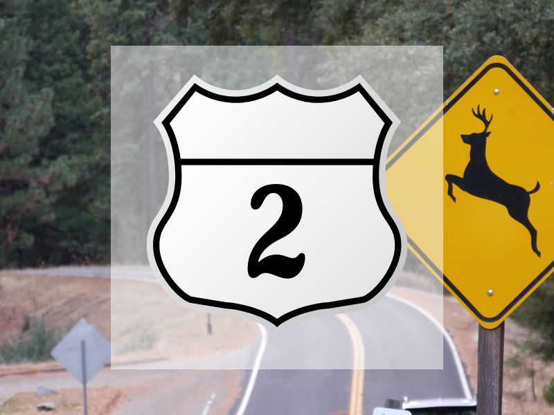 US-2 road sign with deer crossing mountain road background