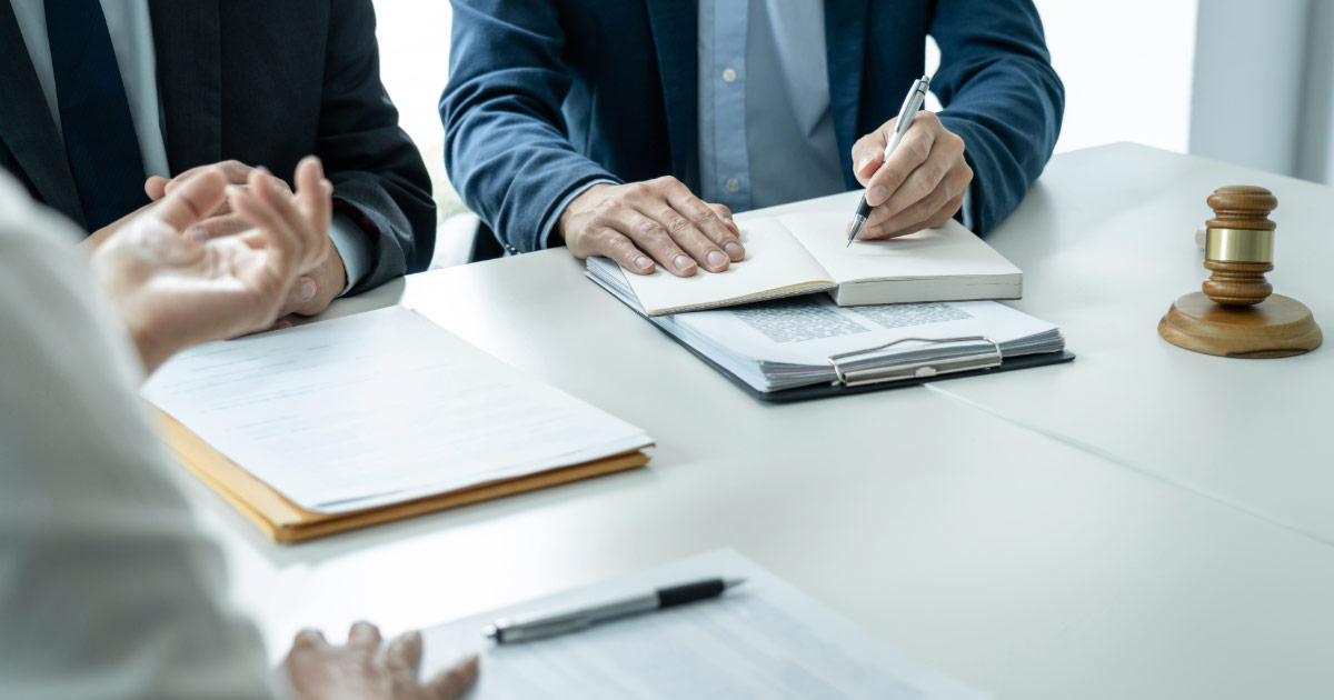 Lawyers taking notes while meeting with client