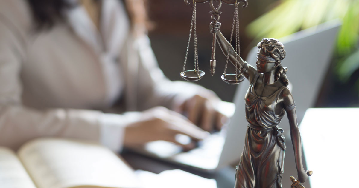 Woman working on her laptop with scales of justice on the desk