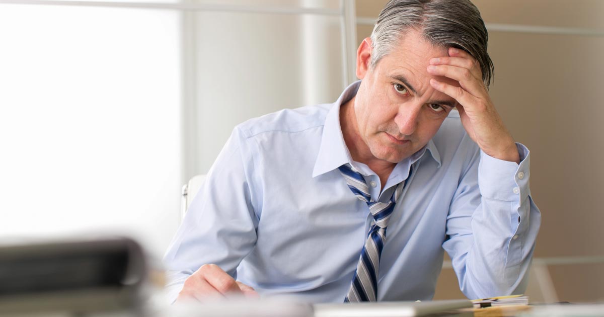 Man in shirt and tie holding his head in frustration
