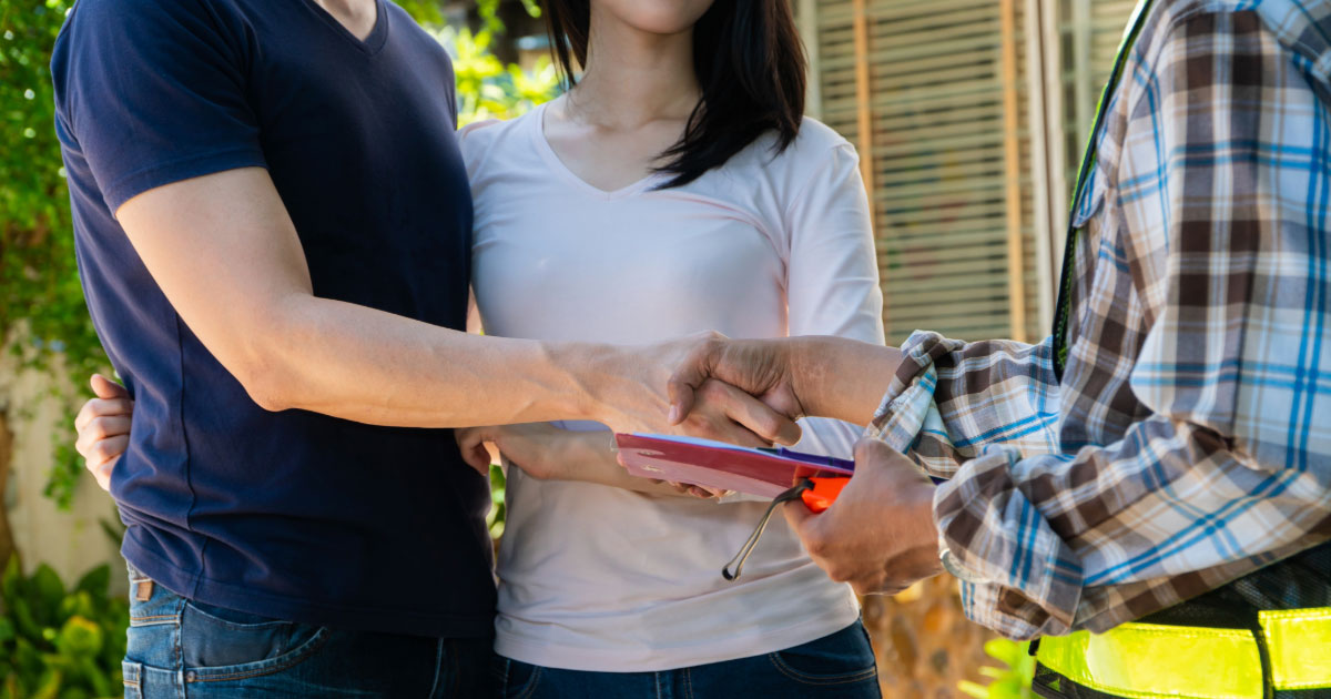 Young couple shaking hands with remodeling contractor
