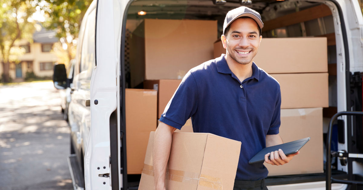 Delivery driver walking towards a home carrying a package