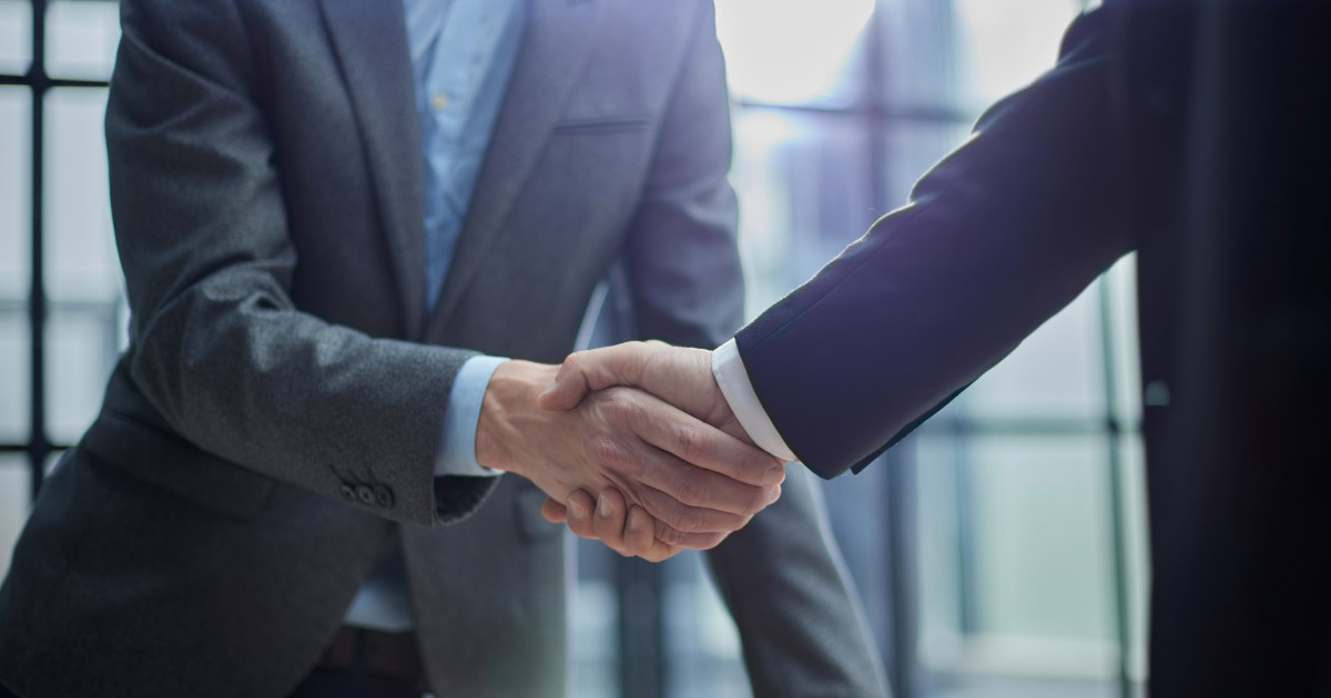 Two men wearing suits shaking hands